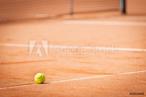 Bild på yellow tennis ball on orange sand and white lines